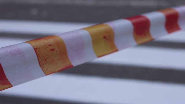 Road construction in the city. The passage is closed. A warning barrier tape flutters in the wind. construction industry content, safety training materials, planning projects