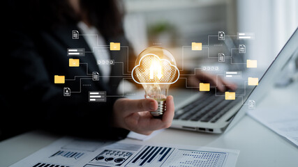 Obraz na płótnie Canvas A modern office scene featuring a light bulb symbolizing innovation and cloud computing concepts, complemented by a laptop and data visualizations, inspires creativity. Gantry