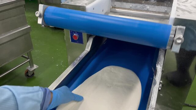 Dough being mixed and kneaded in an industrial mixer during food manufacturing operations. Continuous mixing process used to develop dough structure, improve consistency, and support large-scale baker