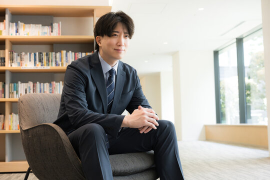 Portraits of handsome young executives, CEOs, and businesspeople smiling as they sit in front of a bookshelf