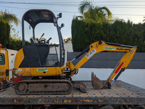 Marratx&iacute;, Mallorca, Spain &ndash; May 11, 2025: JCB 8018 CTS compact tracked mini excavator on trailer parked in residential street. Construction machinery, excavation machine, earthmoving equipment.