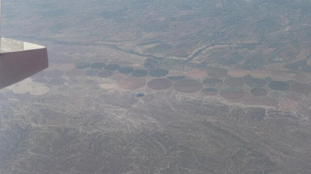 Aerial View of Agricultural Circles: A bird's eye view reveals circular fields created by irrigation systems, showcasing agricultural patterns in a vast arid landscape.