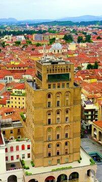 Vertical video. Brescia, Italy. Palazzo delle Poste, the austere ochre and white post office tower dominating Piazza della Vittoria, Drone footage over the rationalist square and terracotta rooftops.