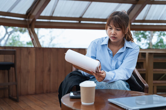 Woman in blue shirt is focused on data and analysis while planning financial tasks and discussion in cozy wooden room with coffee cup and laptop on table