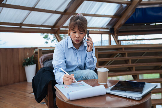 Young woman working on financial planning with data analysis and discussion using documents and digital devices in cozy wooden office space