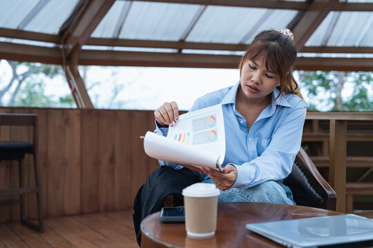 Woman engaged in financial planning and data analysis while reviewing charts and graphs during focused discussion in casual workspace with coffee and laptop nearby