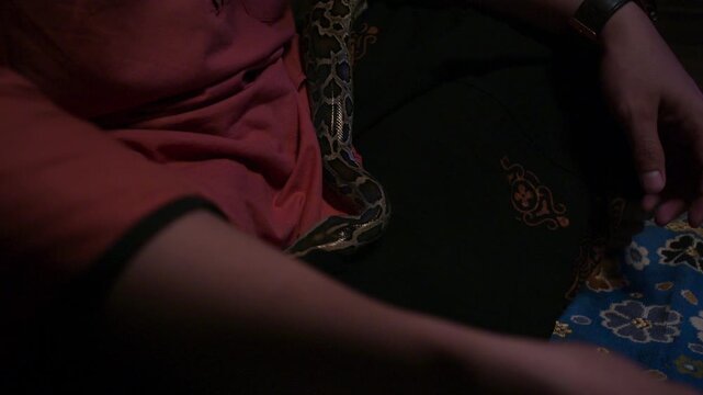 Snake Coiled Around Seated Man in Dark Atmospheric Scene