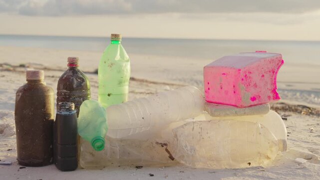 Single use plastic on white sandy beach pollution concept, stop motion, environmental cleanup and issues