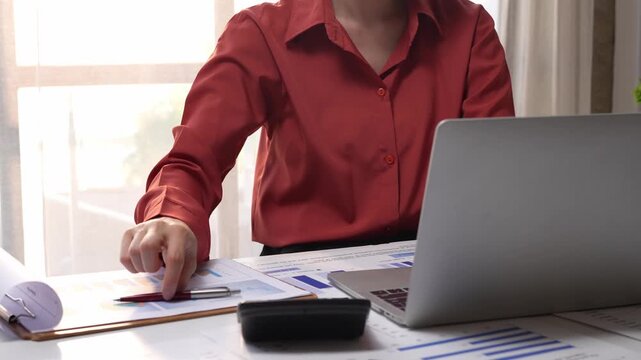 Businesswoman analyzing financial data on laptop and documents