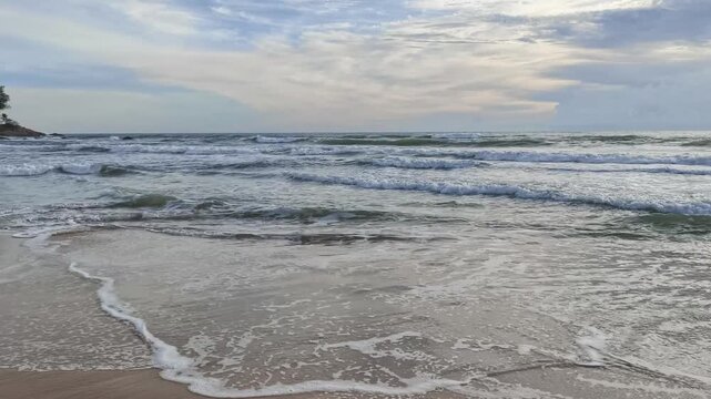 Sea waves on the beach with cloudy sunset sky background.