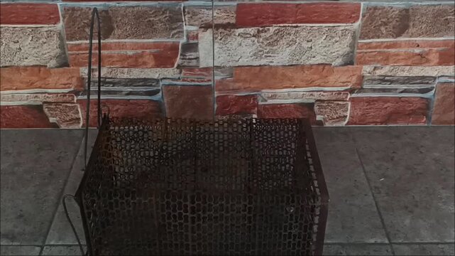 Vintage iron mesh live animal catcher trap with surface rust, used for humane pest control on cement surface