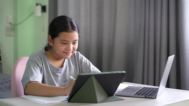 asian child student write learning on computer tablet screen or kid girl fun studying writing to drawing with video call on study online class by laptop notebook or young people learn from home school