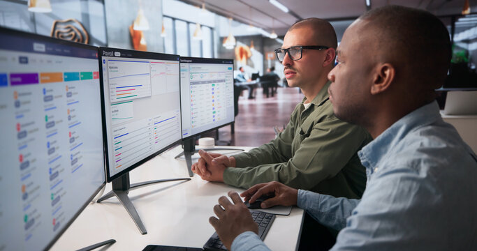 Two Team Members Analyzing Payroll Data On Computer