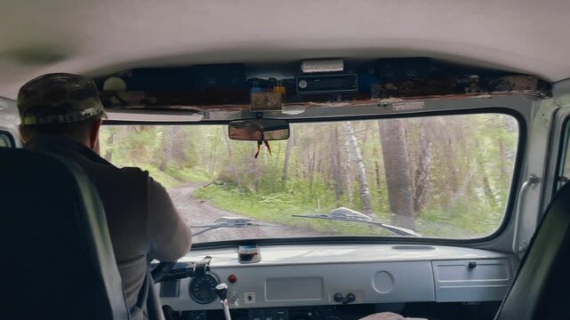 Point of view from inside a vehicle driving along a rough forest road toward Ak-Kem Valley in the Altai Mountains, Altai Republic, Russia, adventure travel concept