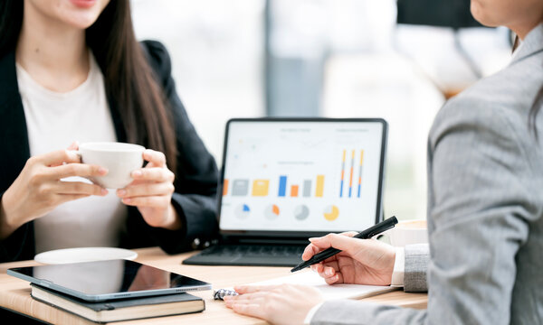 Businesswomen analyzing financial dashboard on tablet in office.