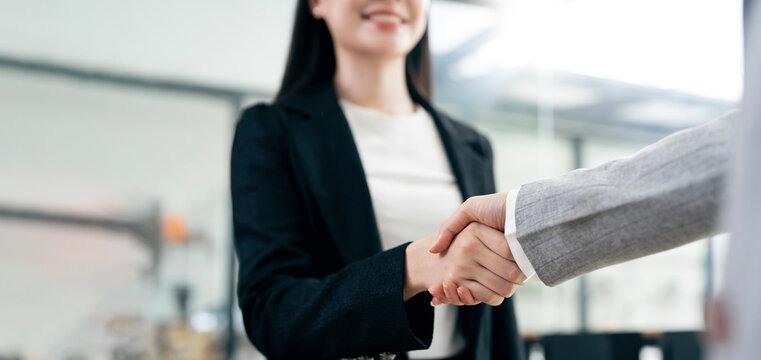 Close-up of business people shaking hands in office.