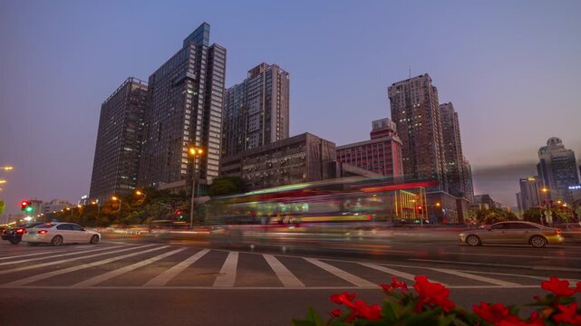 Evening cityscape time-lapse with busy road traffic, modern buildings, and twilight changing to night.