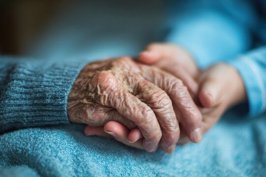elderly hand held gently by younger hand