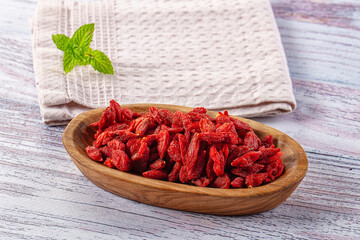 Organic dried goji berries in wooden bowl with fresh mint leaf © Andrei Starostin