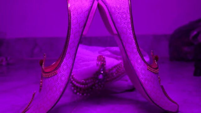 Cinematic close-up of traditional Indian groom's jutti (mojari) shoes featuring intricate embroidery and elegant craftsmanship. The luxurious ethnic footwear is displayed before the wedding ceremony.