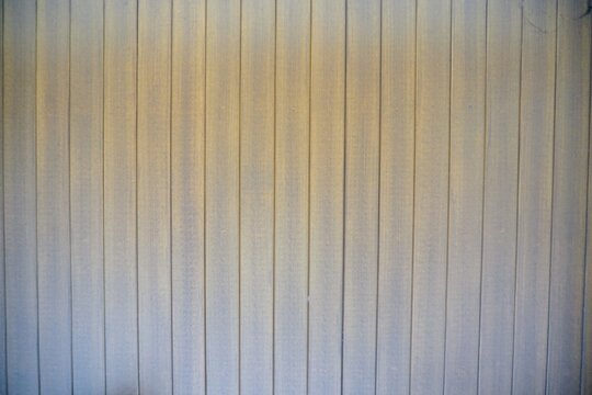 Texture of a vertical corrugated metal wall surface with a weathered brownish color gradation.