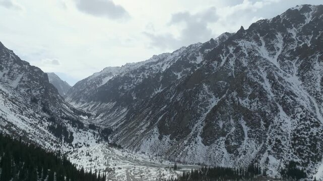 Wide aerial footage of rugged snow-covered peaks and a winding river valley in Ala-Archa National Park near Bishkek, Chuy Region, Kyrgyzstan
