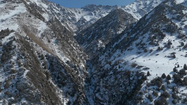 Drone footage of the Issyk-Ata Gorge with steep rocky slopes, scattered trees and fresh snow in the Tian Shan mountains near Bishkek, Chuy Region, Kyrgyzstan