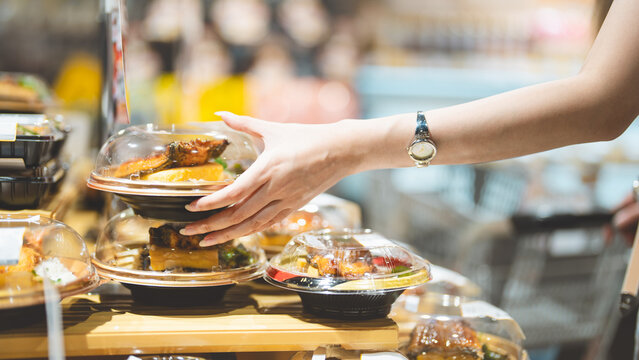 Young adult asian single woman customer choosing ready meals cooked food from shelf at asia supermarket