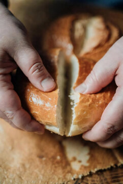 Close-up of hands breaking bread, warm tones, sensory food experience, soft light