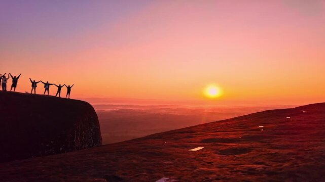 Silhouetted travelers gather on the massive rock formation of Three Whale Rock, watching the first light of day spread across the misty countryside of northeastern Thailand.