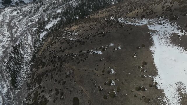 Drone footage of rugged snow covered mountains, pine forest slopes and winding river valley in Ala Archa National Park, Chuy Region, Kyrgyzstan