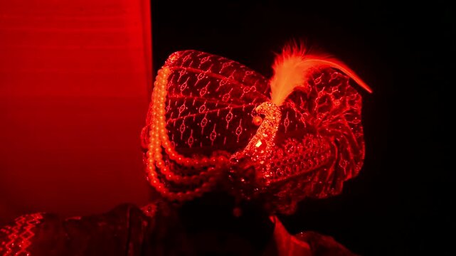 Close-up footage of a traditional Indian groom wedding turban (Safa or Pagdi) decorated with an ornamental brooch, gemstones, and white feather. The ceremonial headwear is an essential part of groom.