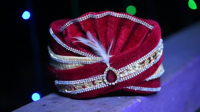 Close-up footage of a traditional Indian groom wedding turban (Safa or Pagdi) decorated with an ornamental brooch, gemstones, and white feather. The ceremonial headwear is an essential part of groom.