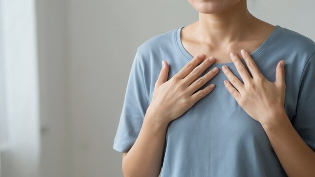 Woman Touching Her Chest Feeling Heart Pain or Difficulty Breathing
