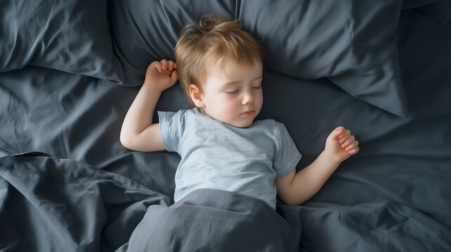 Toddler sleeping peacefully on a soft grey bed, promoting rest, comfort, and a serene atmosphere