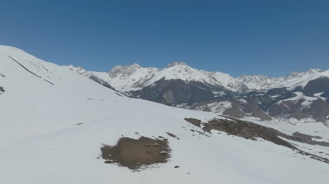 Wide scenic footage of snow-covered ridges and rocky slopes in Grigoryevskoe Gorge, Issyk-Kul Region, Kyrgyzstan, with distant peaks under blue sky