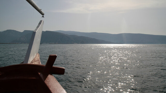 View from the bow of a traditional dhow crossing a sunlit fjord, Musandam, Oman