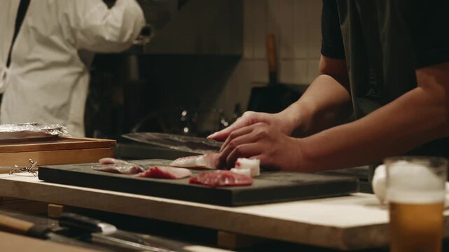 Close-up of skilled male hands preparing sashimi from fresh fish in a small traditional Japanese kitchen, showcasing precision knife work, culinary craftsmanship, and authentic Japanese cuisine.