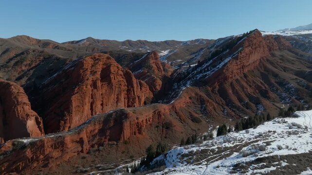 Drone footage of the Seven Bulls red sandstone rock formations and rugged ridges in Jeti Oguz Gorge, Issyk Kul Region, Kyrgyzstan on a clear winter day