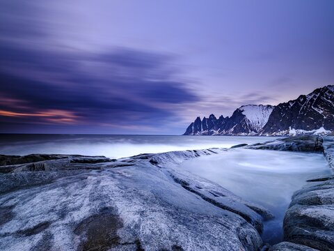Natural pool on granite beach, Devils Teeth mountain peak in the back, Okshornan mountain range, Tungeneset, Senja Island, Troms, Norway