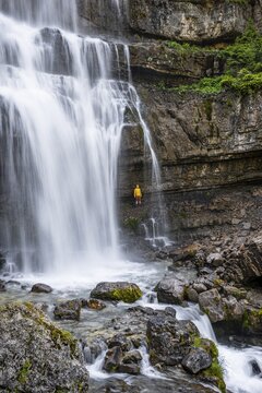 Adventure, Little hiker under large Cascata di Mezzo waterfall, long exposure, Vallesinella, Brenta, Trentino, Italy