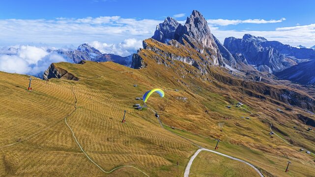 Paraglider over alpine meadows, in the background the peaks Sas Rigais and Furchetta of the Odle group, drone shot, Val Gardena, Dolomites, Autonomous Province of Bolzano, South Tyrol, Italy