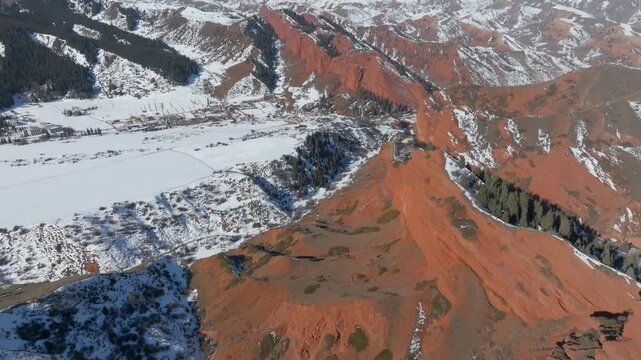 Aerial winter landscape of Jeti Oguz Gorge and the Seven Bulls red sandstone cliffs, with snow-covered valley, forests and mountains near Karakol, Kyrgyzstan