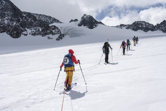 High altitude tour, ski tourers walking on a rope over Alpeiner Ferner glacier, winter in the mountains, Neustift im Stubai Valley, Tyrol, Austria