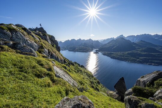 Mountaineer on the summit of Dronningsvarden or Stortinden, behind sea and fjord Umv&aring;gsundet, Sonnenstern, Vester&aring;len, Norway
