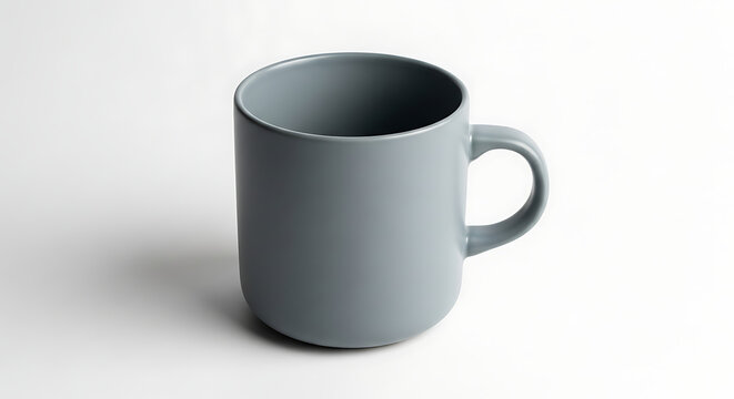 A simple gray mug with a handle sitting on a white surface in a well lit studio setting showing shadows