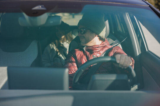Smiling man driving an electirc car on a road trip