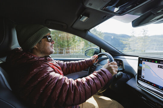 Happy man driving a modern car on a scenic road trip
