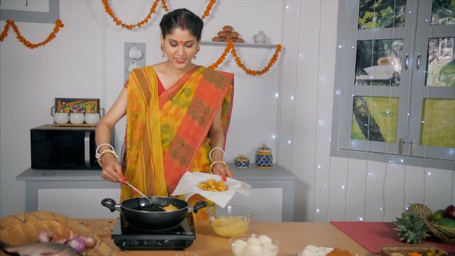 A beautiful Bengali woman frying tasty cutlets (Aloo Chop) for her family members. A medium shot of an attractive Indian lady in Bengali style saree making evening snacks (pakoras) - Traditional In...