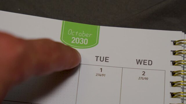 finger pointing at October 2030 planner page close up for scheduling and monthly planning concept